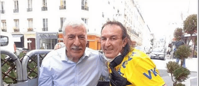 two men are posing for a picture on a city street .