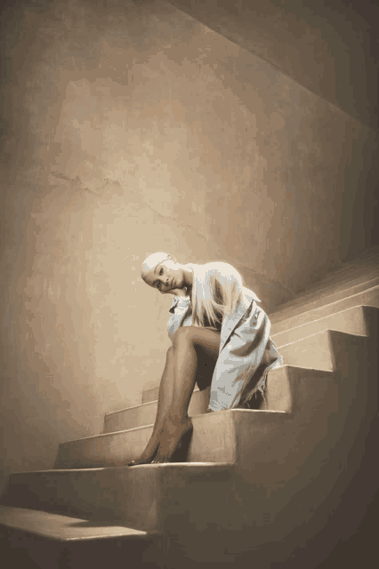 a woman sits on a set of concrete stairs with her legs crossed