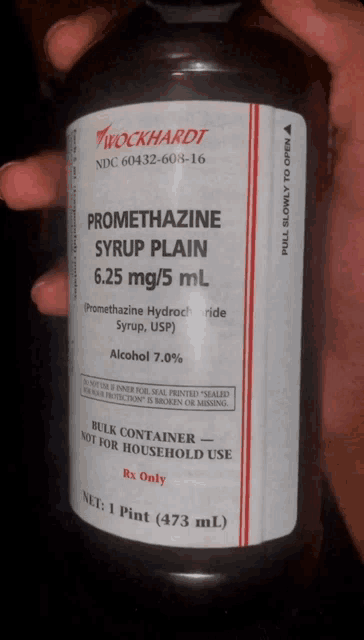 a person is holding a bottle of promethazine syrup