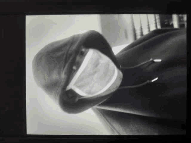 a black and white photo of a person wearing a mask and a hood