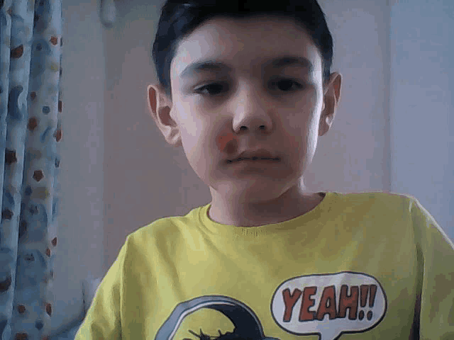 a young boy wearing a yellow shirt that says yeah on it