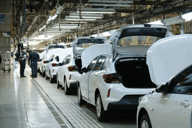 a row of cars in a factory with their trunks open