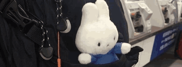 a stuffed bunny is sticking out of a backpack .