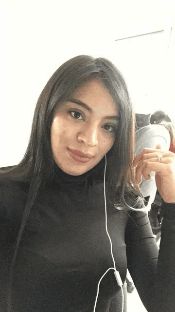 a woman wearing a black turtleneck is taking a picture of herself