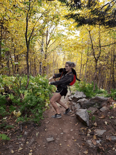 a woman with a backpack is walking down a trail