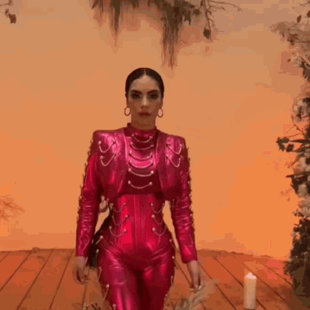 a woman in a pink outfit is standing in front of a candle