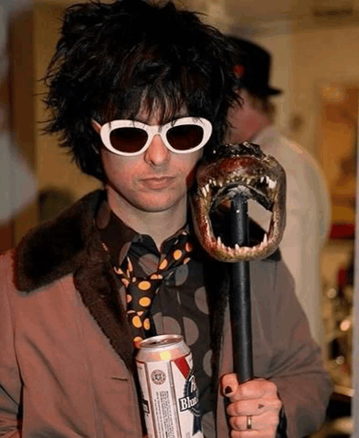 a man wearing sunglasses and a tie is holding a can of beer and a fake alligator head .