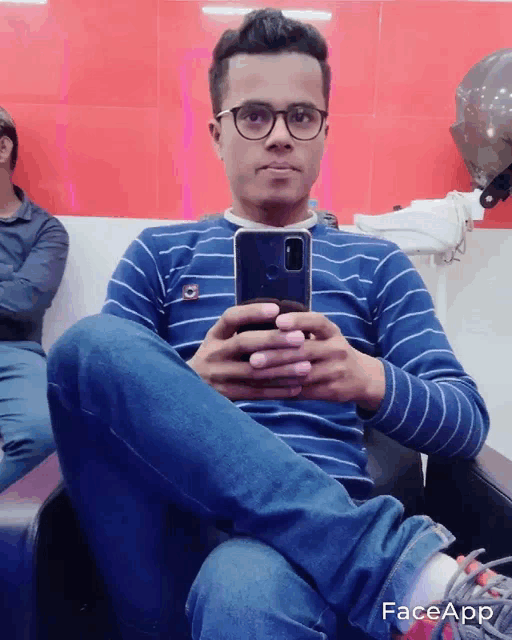 a man wearing glasses and a blue striped shirt is taking a selfie with his phone