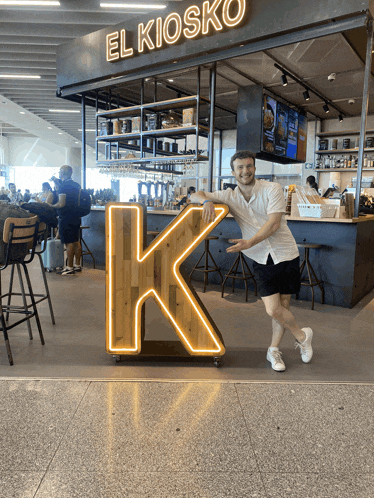 a man stands in front of a el kiosk sign