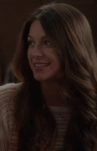 a woman with long brown hair is smiling and looking to the side