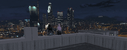 two people sitting on a ledge looking at a city skyline at night