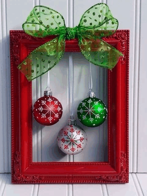 three christmas ornaments are hanging in a red frame