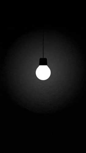 a white light bulb hanging from a ceiling in the dark .