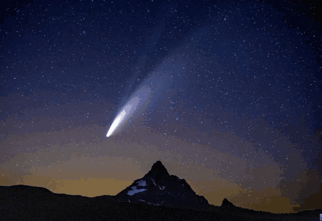 a mountain with a comet in the night sky