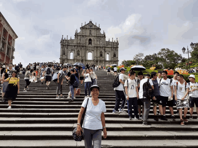 a woman stands on a set of stairs in front of a building with a crowd of people