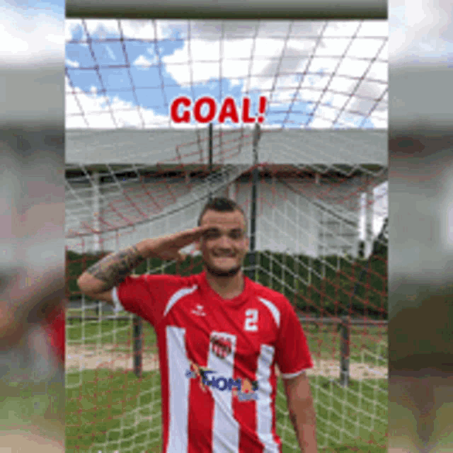 a man wearing a red and white striped shirt with the number 2 on it salutes in front of a goal