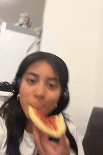 a woman wearing headphones is eating a piece of pizza