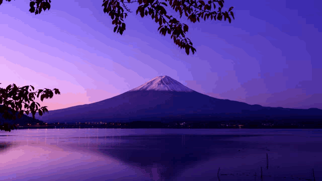 a lake with a mountain in the background and a purple sky