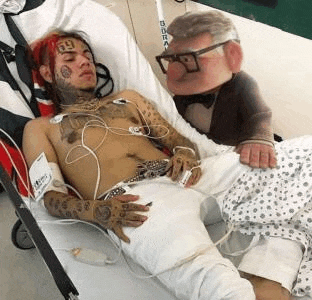 a man is laying in a hospital bed next to a stuffed animal with glasses .