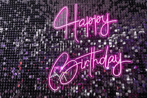 a neon sign that says happy birthday on a wall