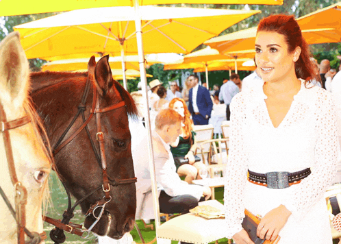 a woman in a white dress stands next to a brown and white horse