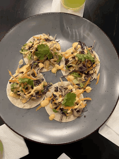 a plate of tacos with coleslaw and sauce on a table