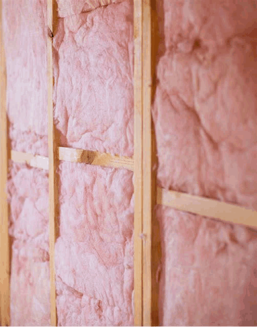 a wall with pink insulation on it and wooden beams