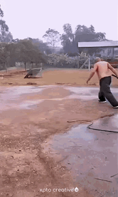 a man in a red shirt is standing on a concrete surface next to a hose with xpto creative written on the bottom right