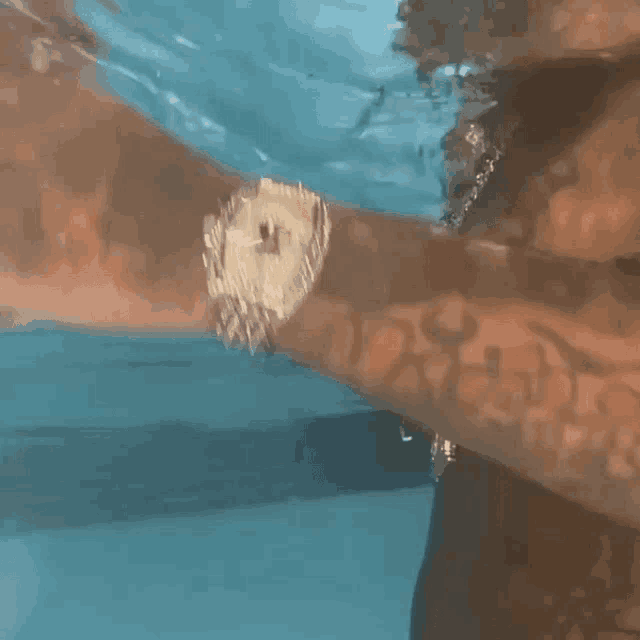 a man is swimming in a pool and wearing a watch on his wrist .