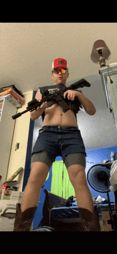 a man wearing shorts and cowboy boots holds a rifle