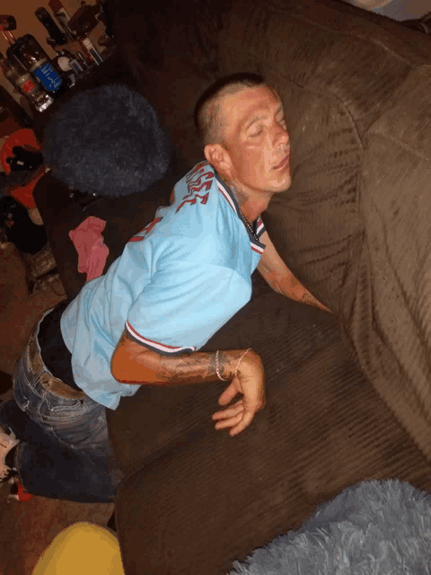 a man laying on a couch wearing a blue shirt that says usa