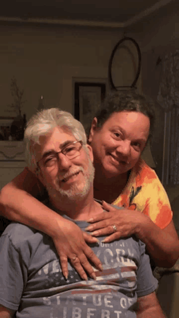 a woman is hugging a man wearing a shirt that says true liberty