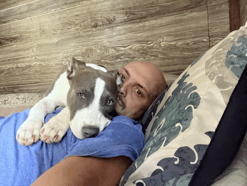 a bald man laying on a bed with a dog