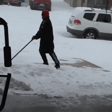 a person is shoveling snow in front of a white suv with a license plate that starts with the letter b