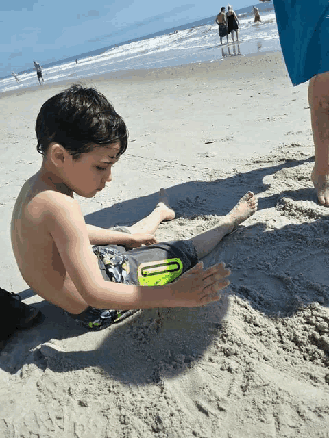 a young boy playing in the sand on the beach