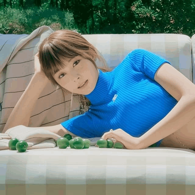 a woman in a blue sweater is laying on a white couch