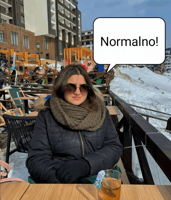 a woman is sitting at a table with a speech bubble that says normalno