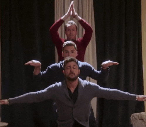 three men are doing a yoga pose with their arms outstretched in front of a window