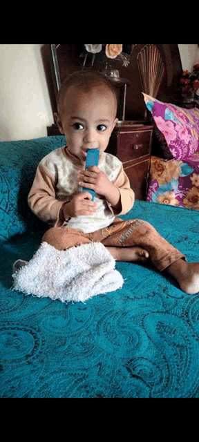 a baby is sitting on a blue couch holding a blue object