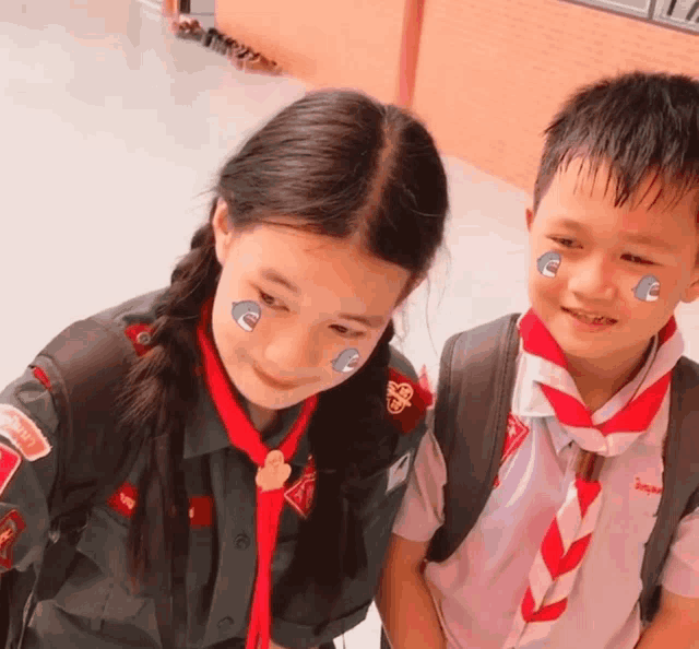 a boy and a girl are posing for a picture and the girl has a sticker on her face that says e on it