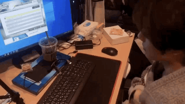 a person is sitting at a desk with a computer monitor and keyboard