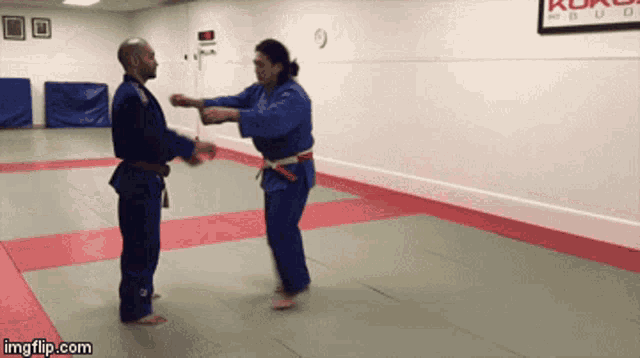 a man and a woman are practicing martial arts in a gym with a sign on the wall that says " koko "