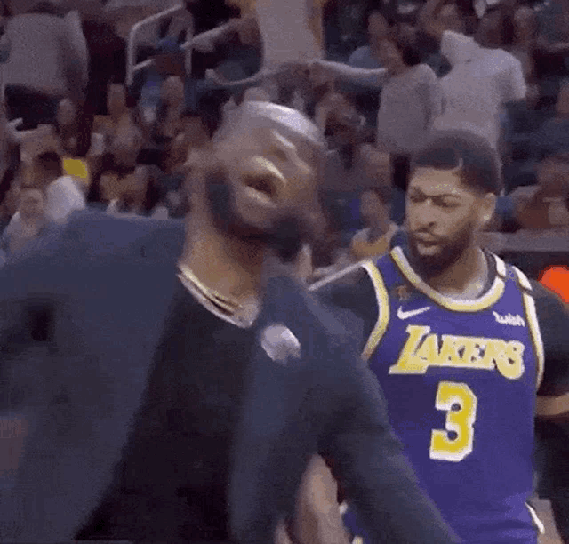 a basketball player in a lakers jersey is standing next to another basketball player .