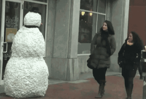 two women are walking past a large snowman in front of a store that says ' o'reilly ' on it