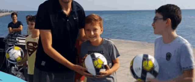 a boy wearing a superman shirt holds a soccer ball