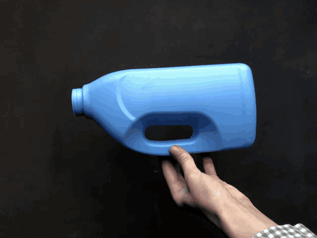 a hand is holding a blue plastic bottle