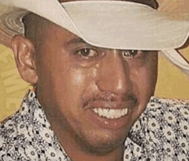 a man wearing a cowboy hat and a floral shirt is smiling .