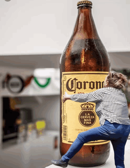 a woman is climbing up a giant bottle of corona