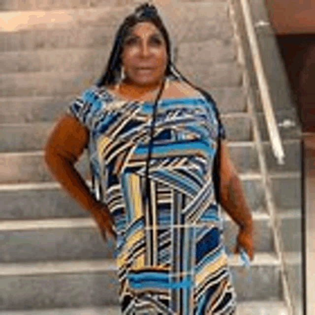 a woman is standing on a set of stairs wearing a blue and yellow dress .