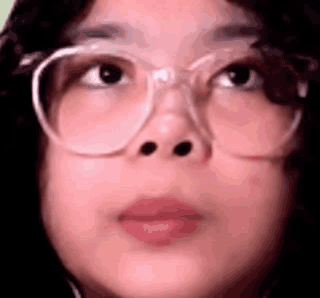 a close up of a person wearing glasses and looking up .